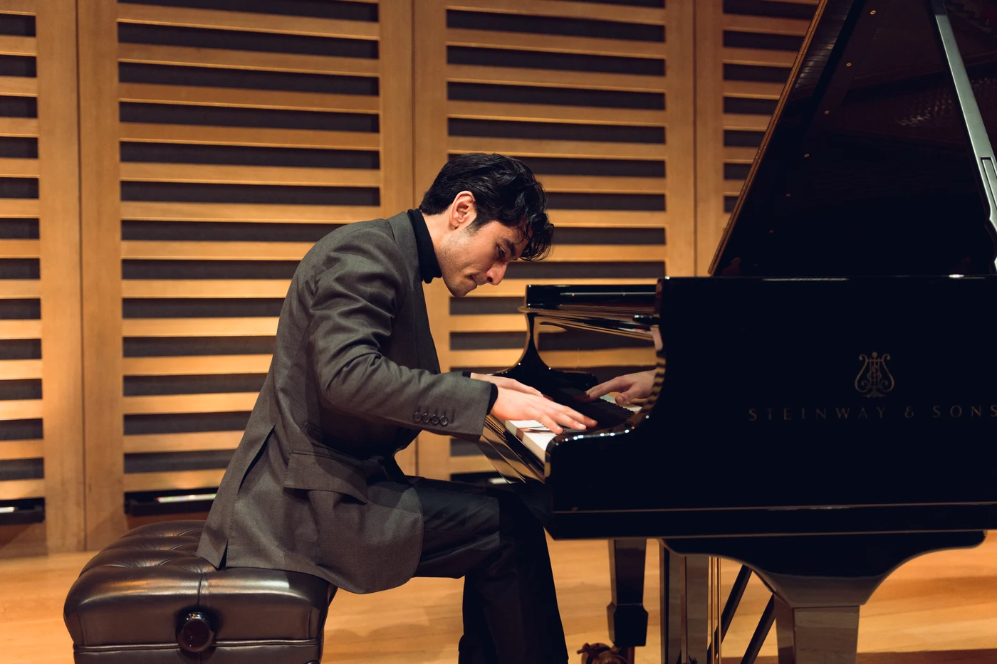 Arsha at the piano in a wood-panelled concert hall